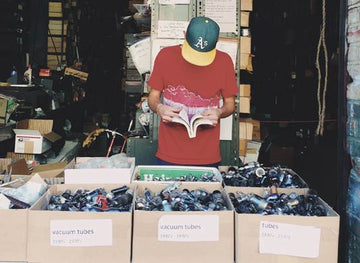 Passive income with thirft shop finds cover photo. A man looking through boxes.