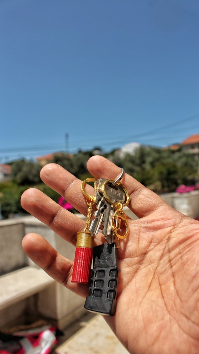 Me holding a mini rifle magazine and shotgun shell 3d printed keychain